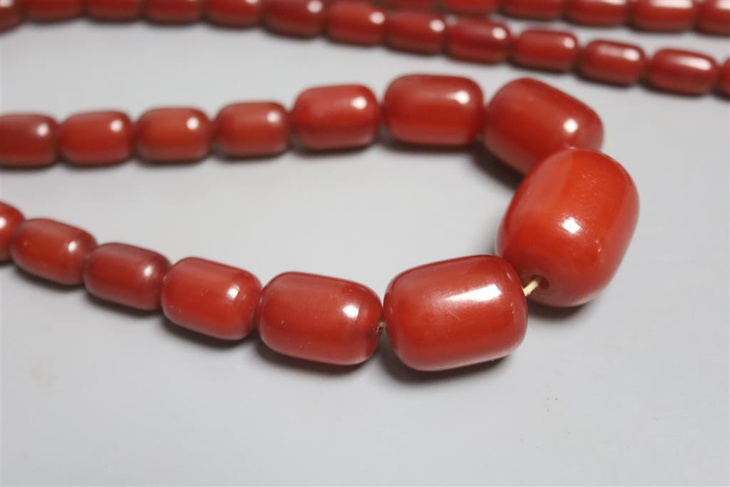 A single strand graduated simulated cherry amber barrel shaped bead necklace, 90cm, gross 87 grams.